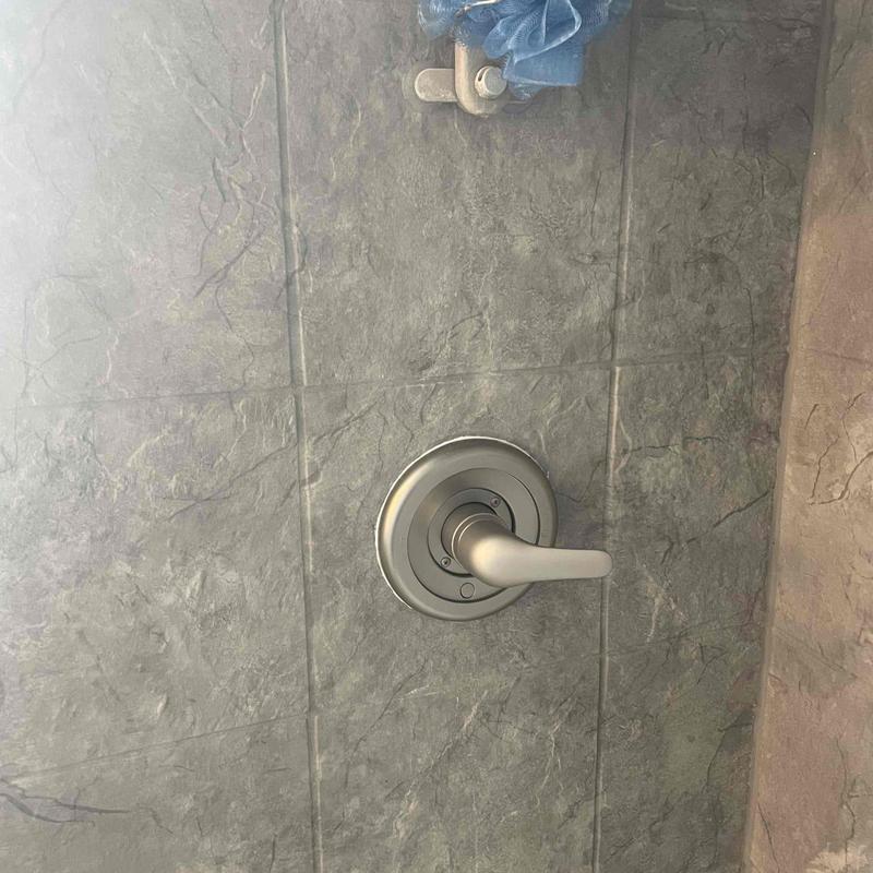 Shower valve handle and trim plate on tiled wall Shower valve handle and trim plate on tiled wall