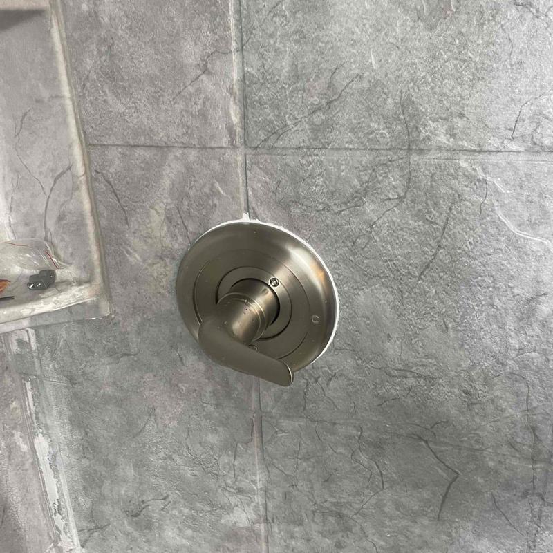 Shower valve handle on gray tile wall Shower valve handle on gray tile wall