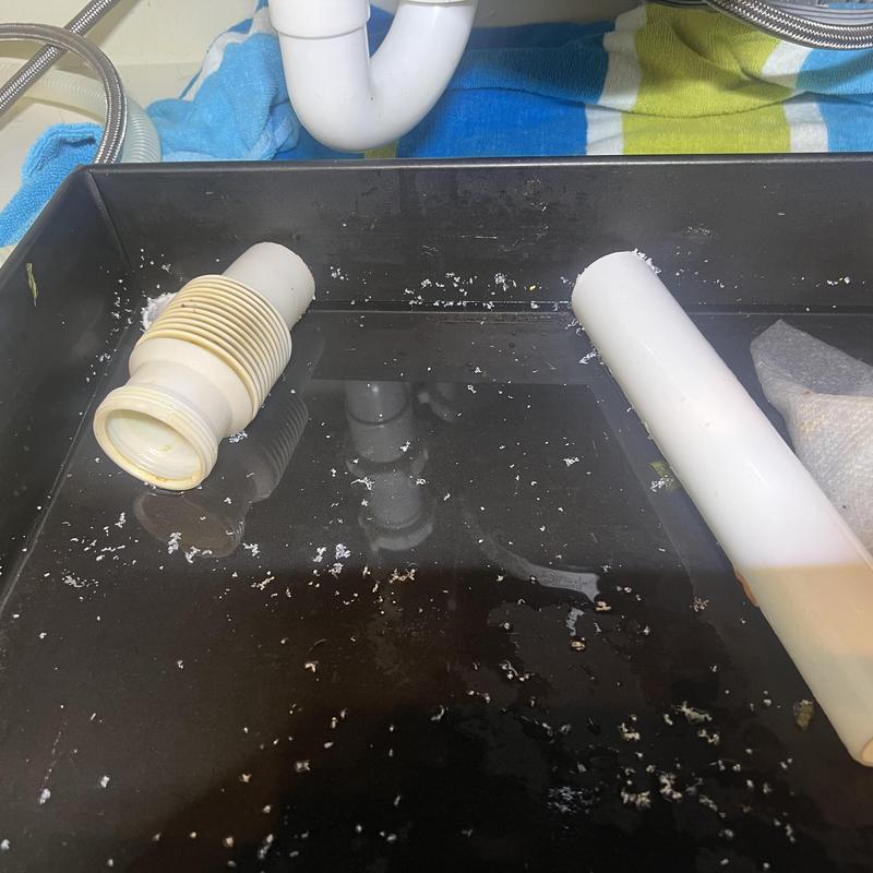 Under sink drain pipes with water leak and debris