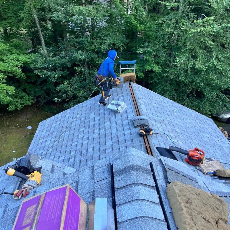 Asphalt shingle roof installation with worker on ridge Asphalt shingle roof installation with worker on ridge