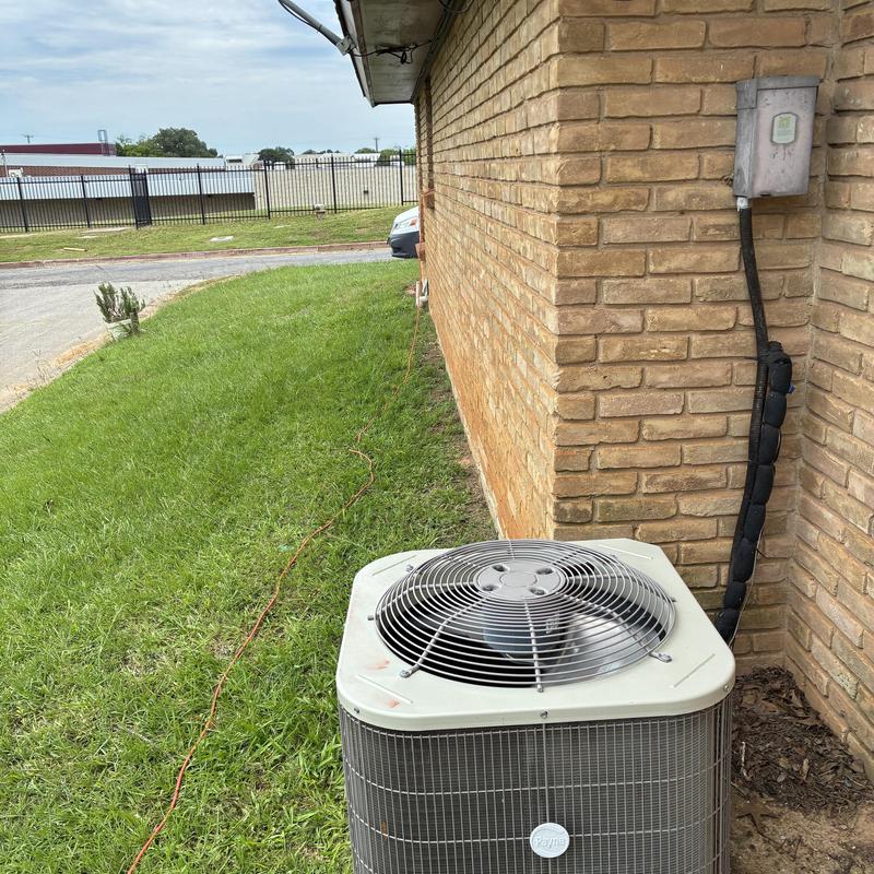 Air conditioner condenser unit beside brick building