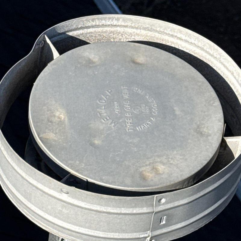 Metal roof vent cap with visible hail dents