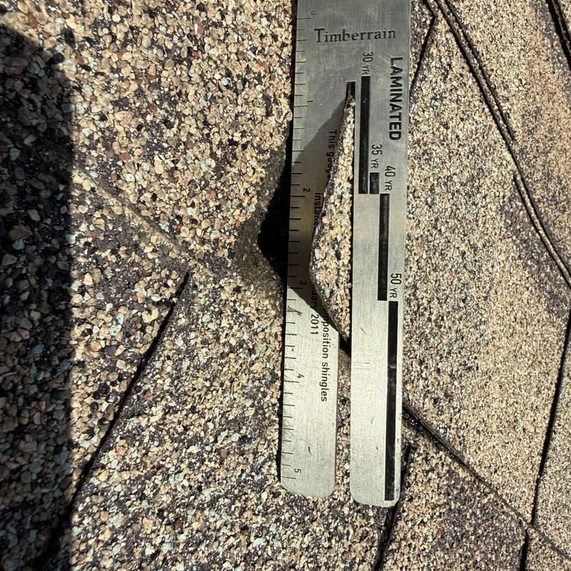 Laminated roof shingles with hail damage and ruler