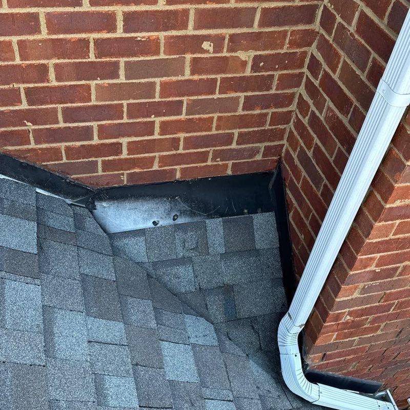 Roof valley with shingle and gutter downspout junction