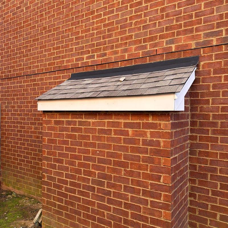 Roof dormer with asphalt shingles on brick structure