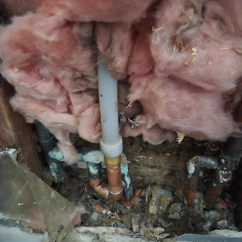Copper and PVC plumbing pipes inside wall cavity with insulation