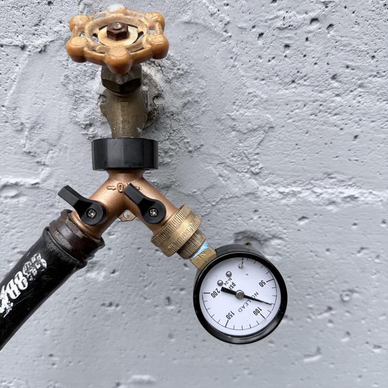 Water meter piping with pressure gauge on exterior wall Water meter piping with pressure gauge on exterior wall
