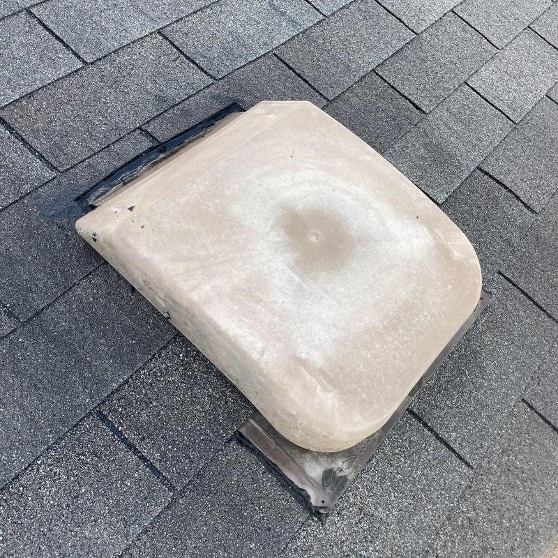 Roof vent cover with worn sealant on shingles