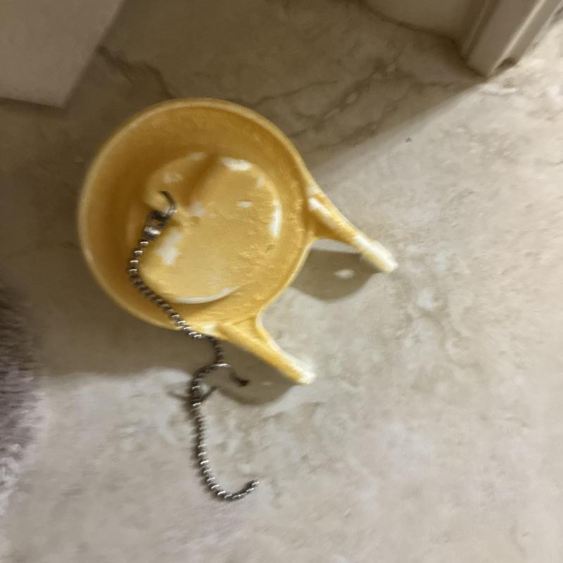 Toilet flapper valve with attached metal chain on floor