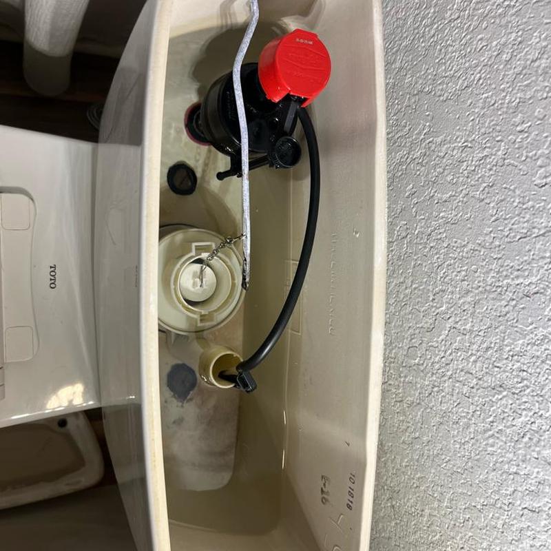 Toilet fill valve with red cap inside tank