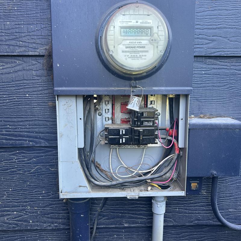 Electrical meter and main breaker panel with wiring exposed