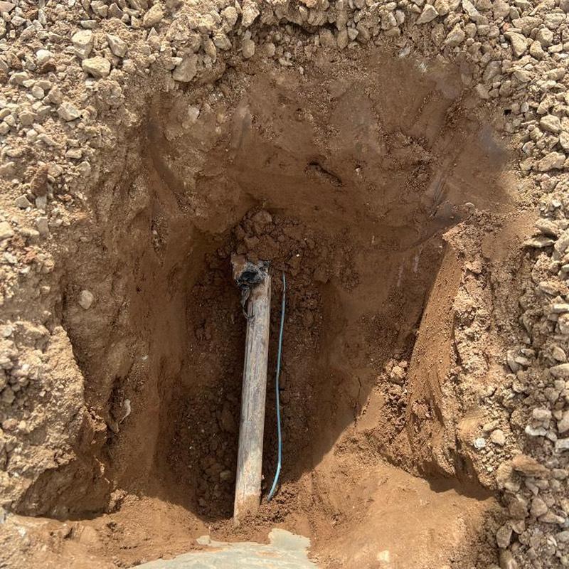 Main water line excavation hole with exposed pipe