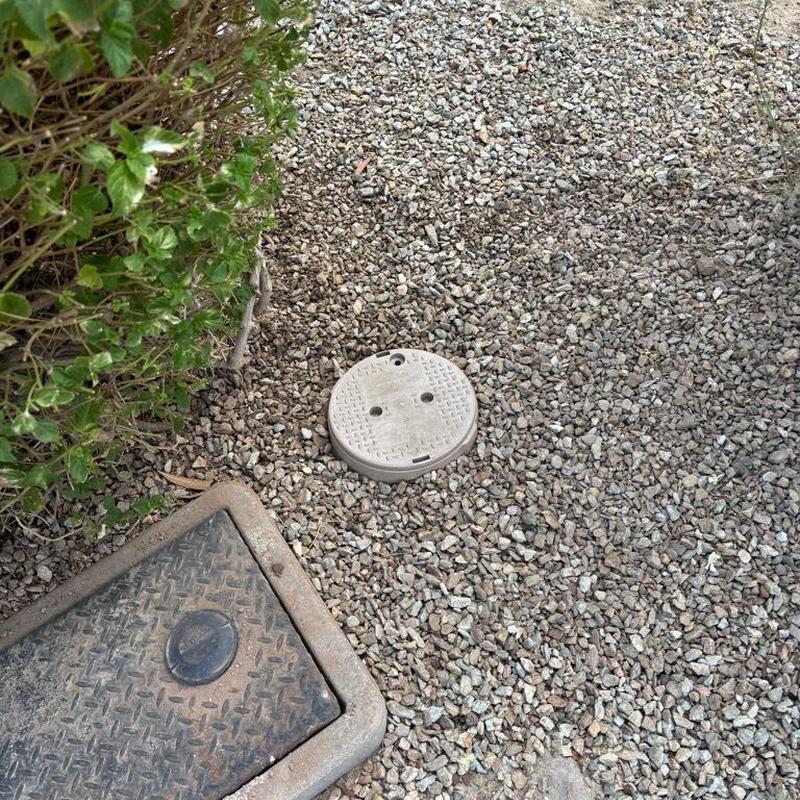 Pressure relief valve with tan access box on gravel