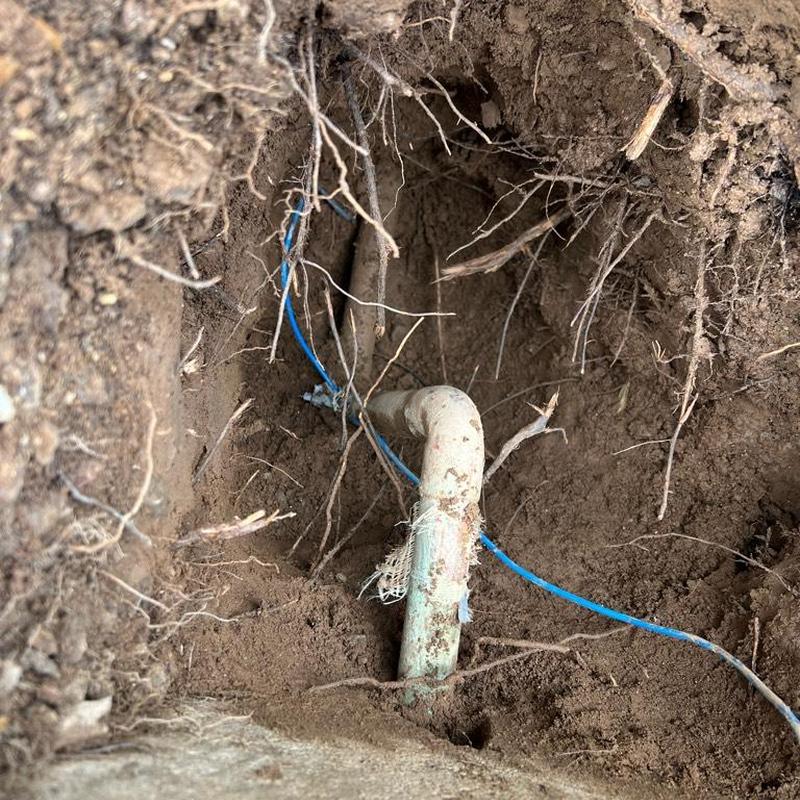 Water line excavation and valve riser installation in dirt.