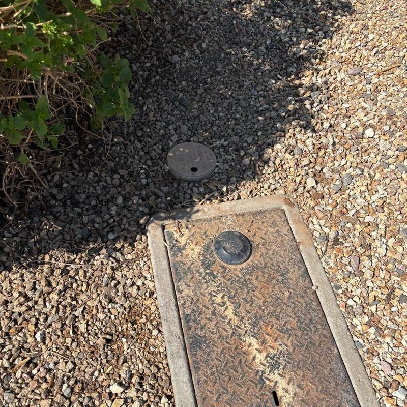 Pressure relief valve access box in gravel ground