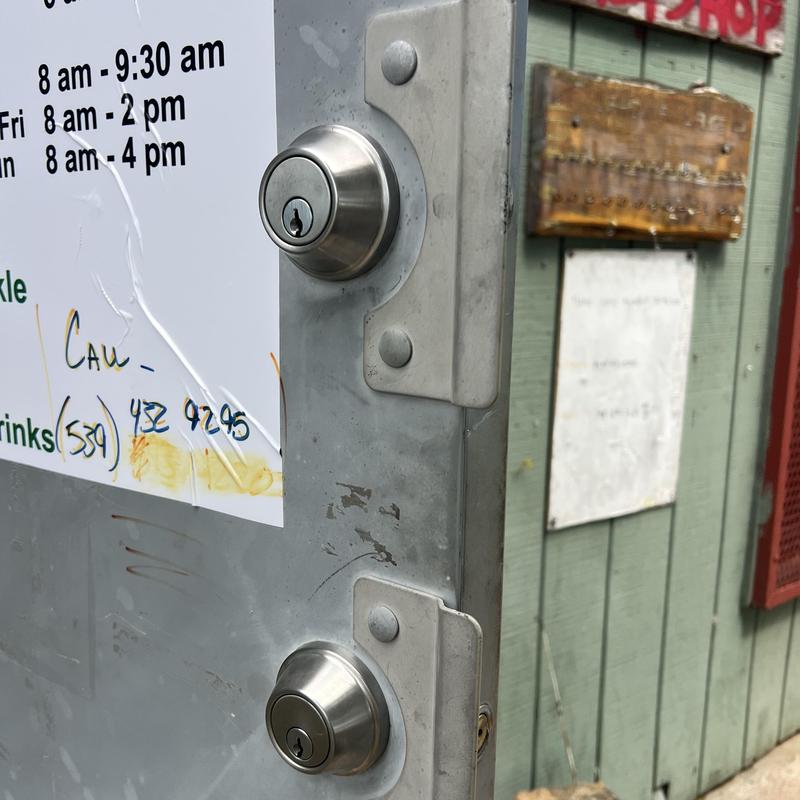 Deadbolt locks on metal business door with signage