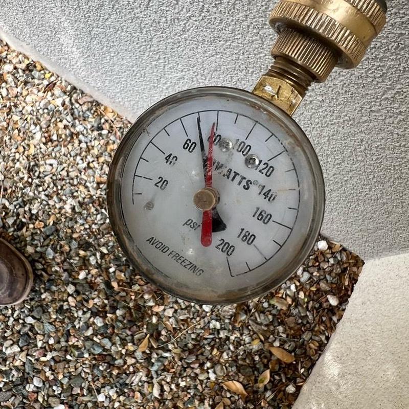 Pressure gauge on water main showing 68 PSI in gravel bed