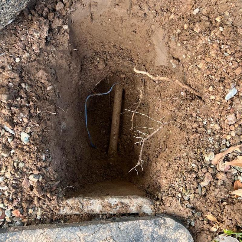 Water main excavation with exposed pipe and wiring