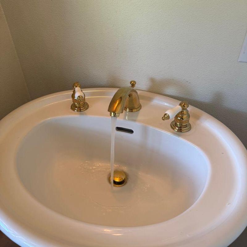 Wide spread faucet on pedestal sink with running water