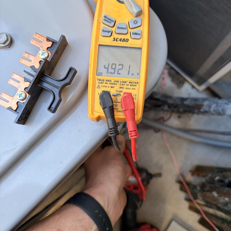 Multimeter measuring voltage on HVAC electrical component