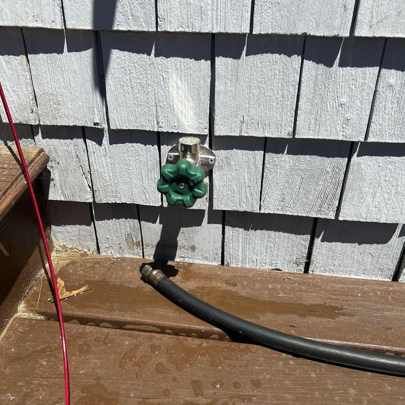 Frost-free sillcock with green handle on exterior wall