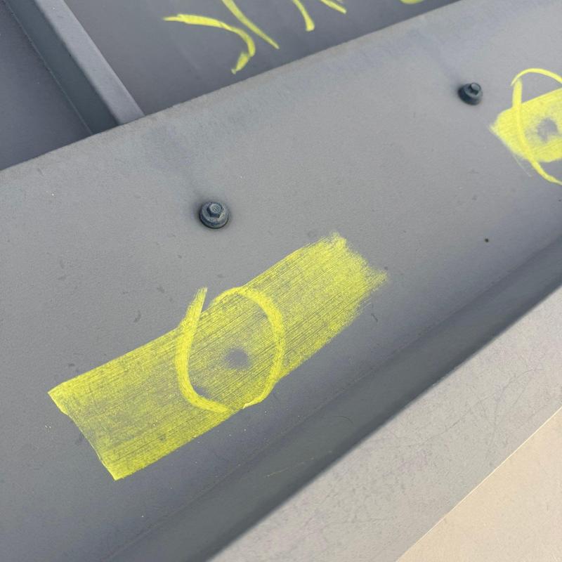 Metal roof panel hail impact marked for repair