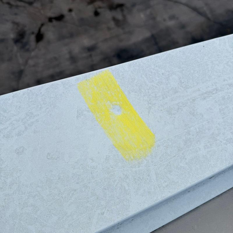 Metal roof panel with hail damage marked in yellow