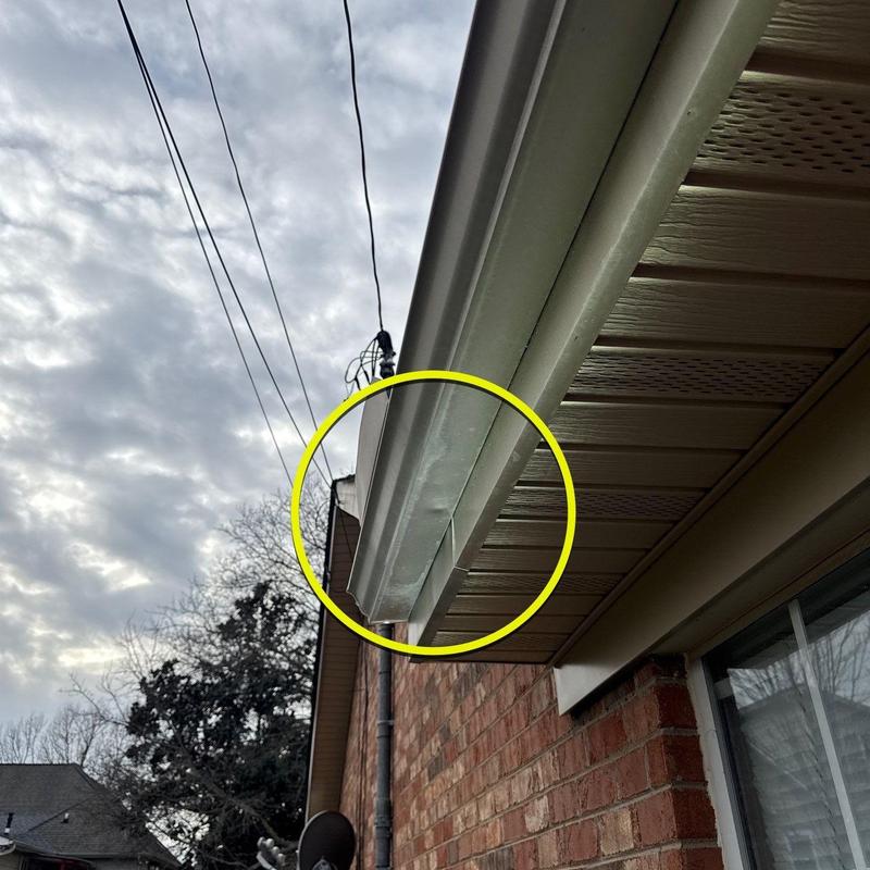 Aluminum gutter dented and misaligned near roof edge