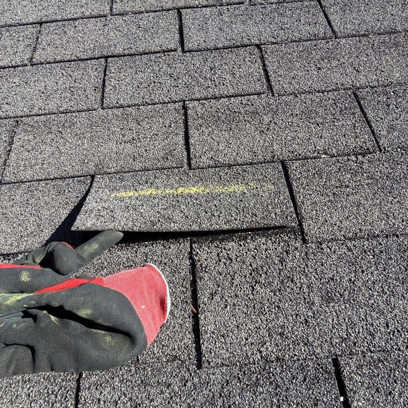 Asphalt shingles with hail damage and glove on roof