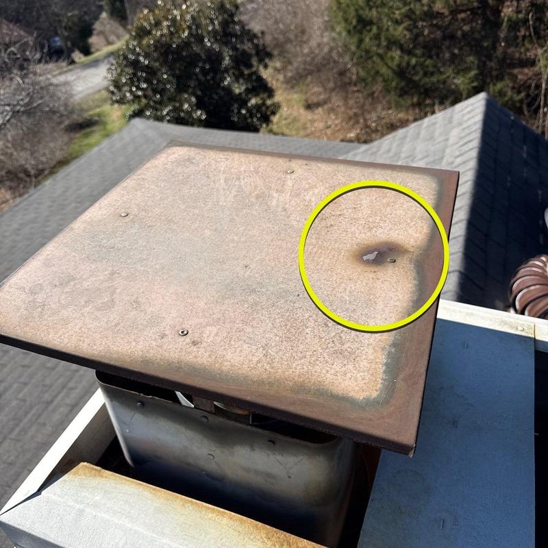Metal chimney cap with rust and damage spot highlighted