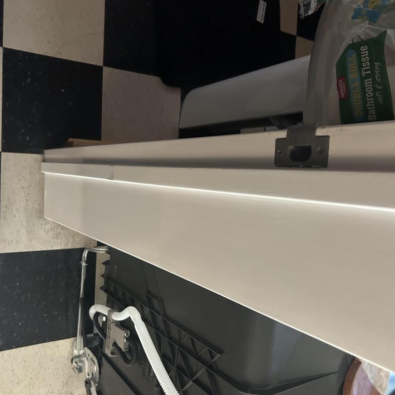 Dishwasher plumbing installation with drain hose visible