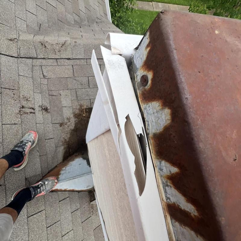 Rusty chimney cap with damaged flashing on roof shingles