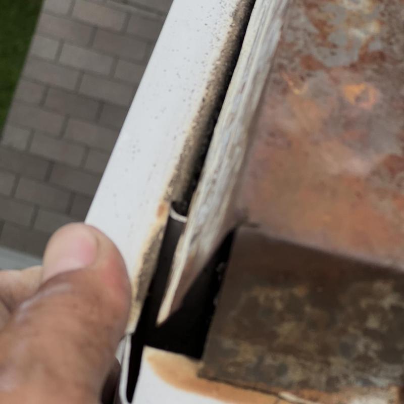 Chimney flashing gap and rust inspection close-up