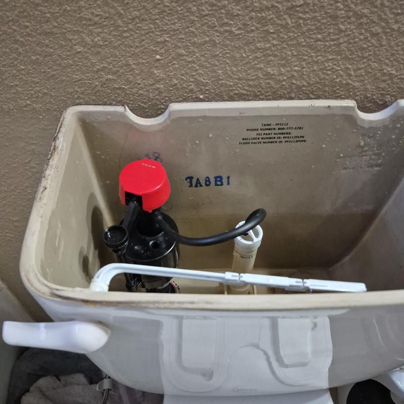 Toilet fill valve with red cap inside tank