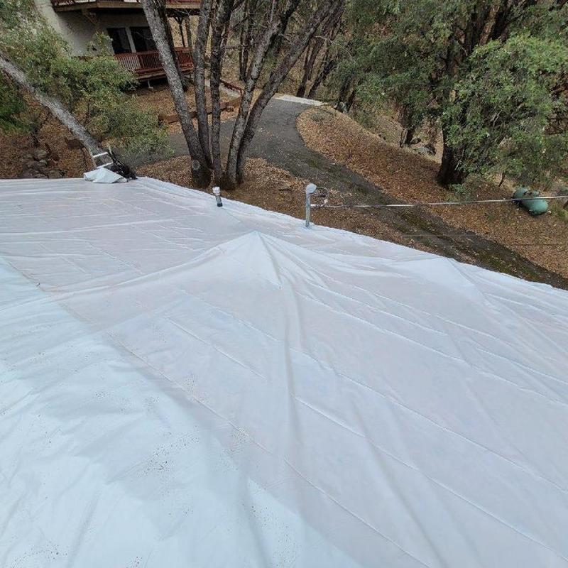 White flat roof membrane installation in wooded area