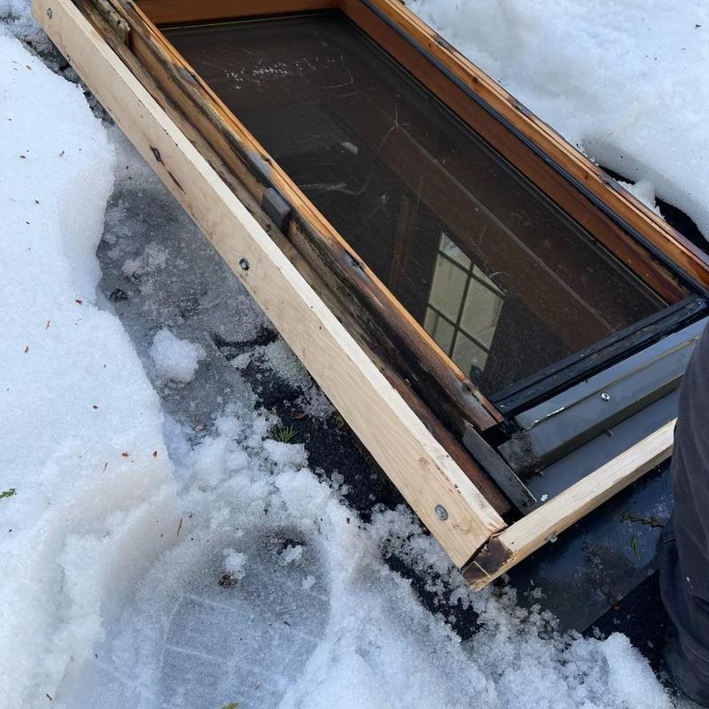 Deck-mounted skylight replacement with wooden frame in snow