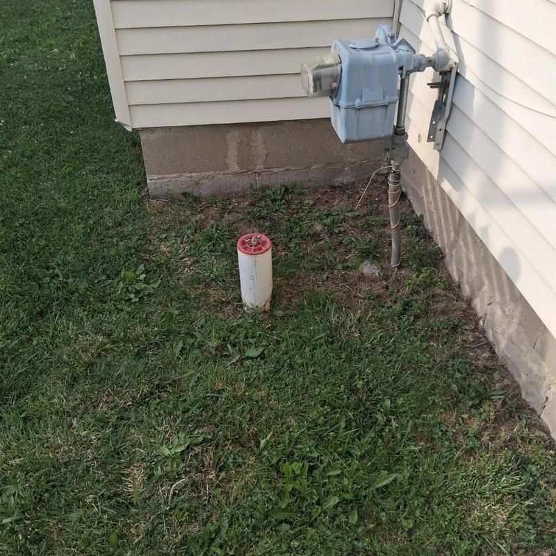 Gas meter and pipe near house foundation