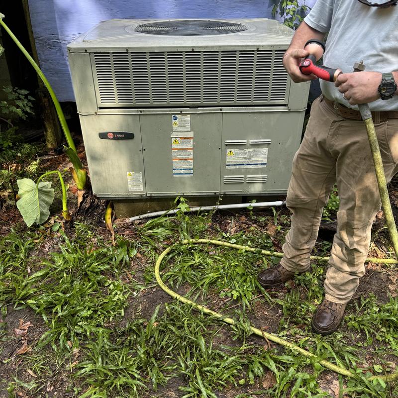 Package unit condenser coil rinsing with hose outdoors Package unit condenser coil rinsing with hose outdoors