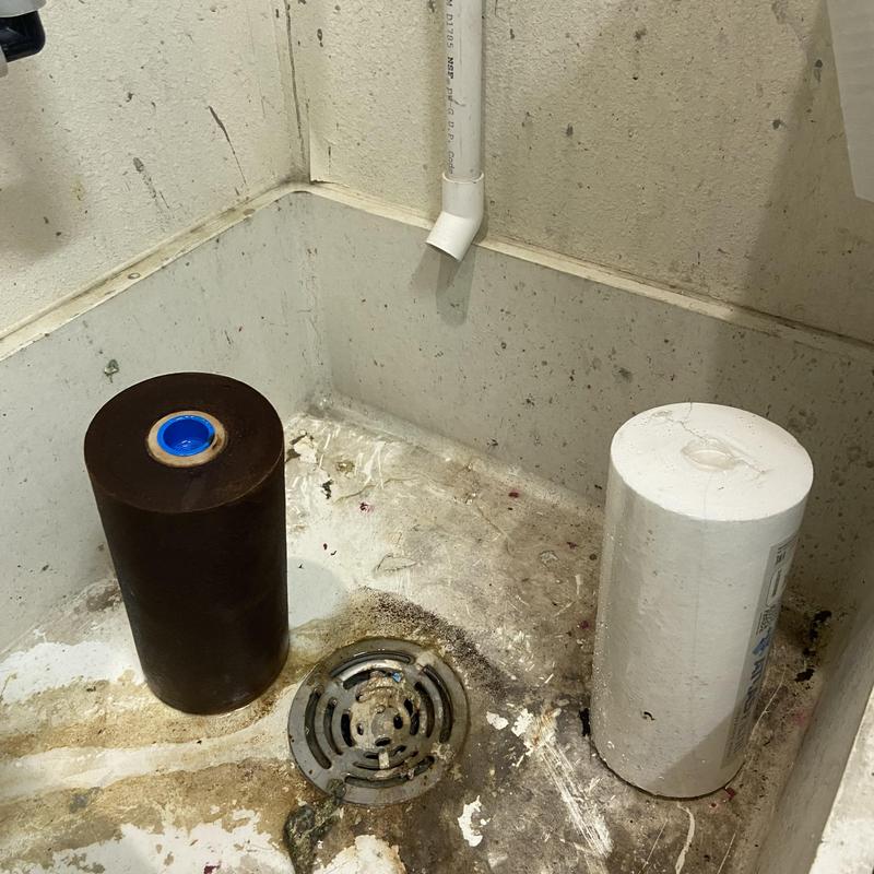Water filter cartridges old and new near floor drain