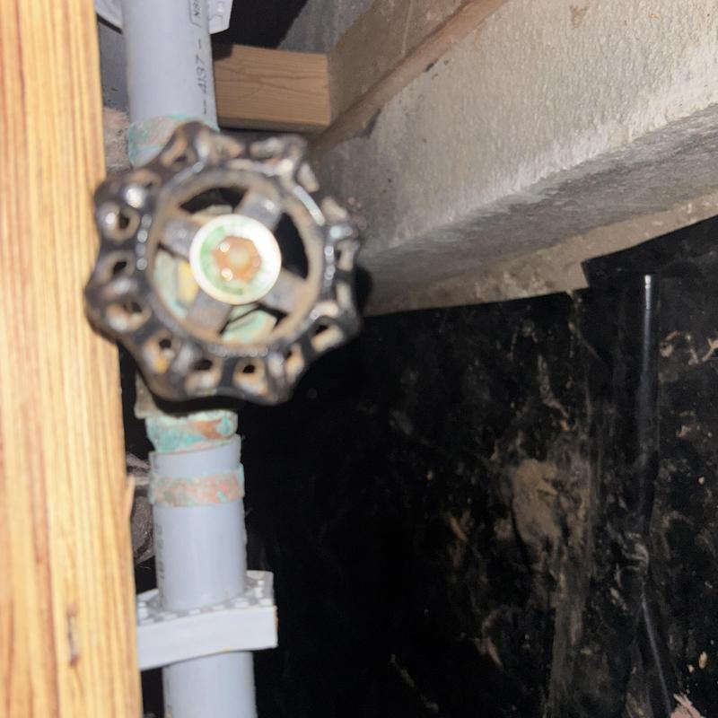 Ball valve on copper pipe in basement corner