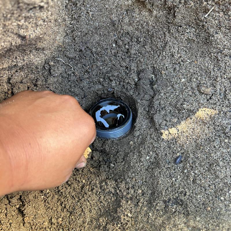 Sprinkler valve buried in soil with hand inspection