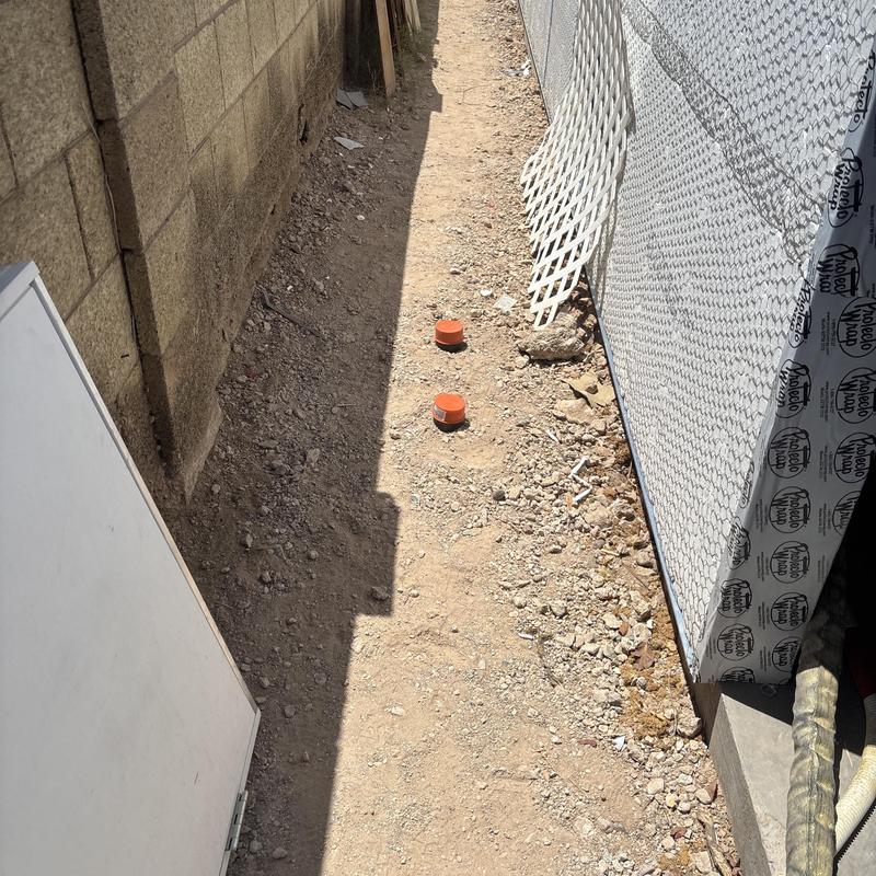 Drain cleanout caps in narrow dirt pathway Glendale AZ