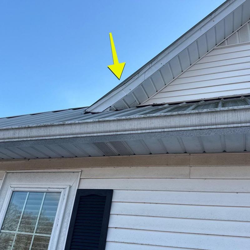 Metal roof flashing with hail damage pointed by arrow