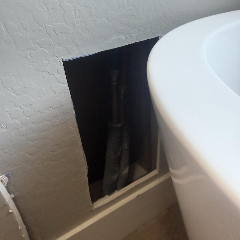 Copper bathroom supply pipes behind wall access panel