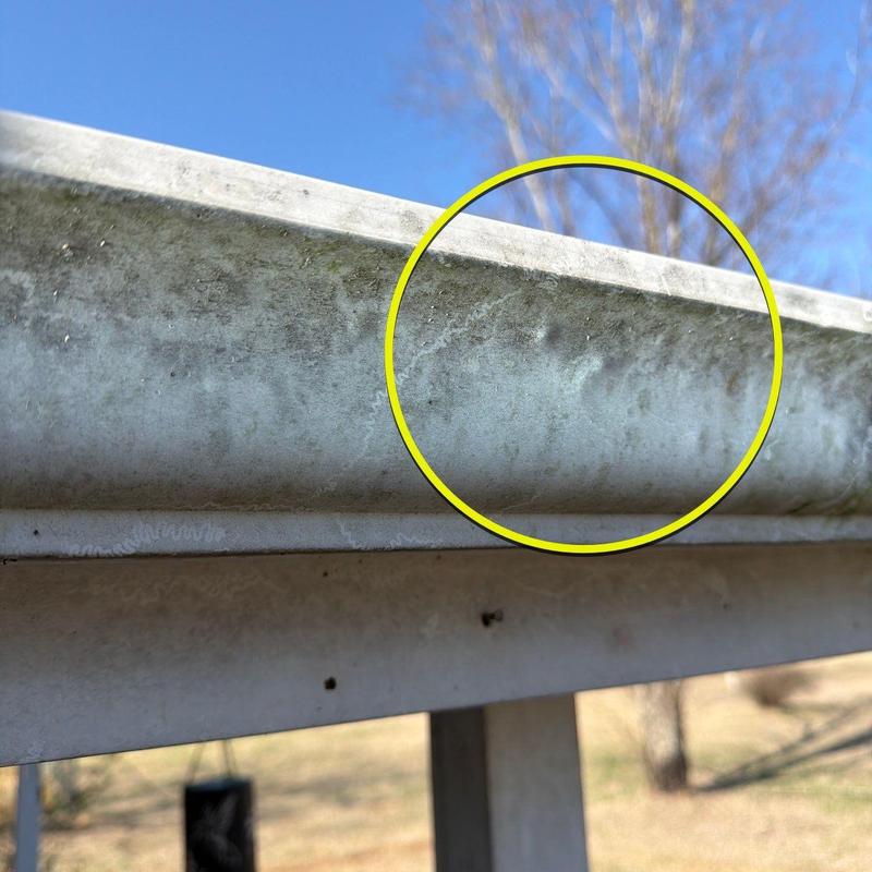 Metal gutter with hail damage and dents highlighted
