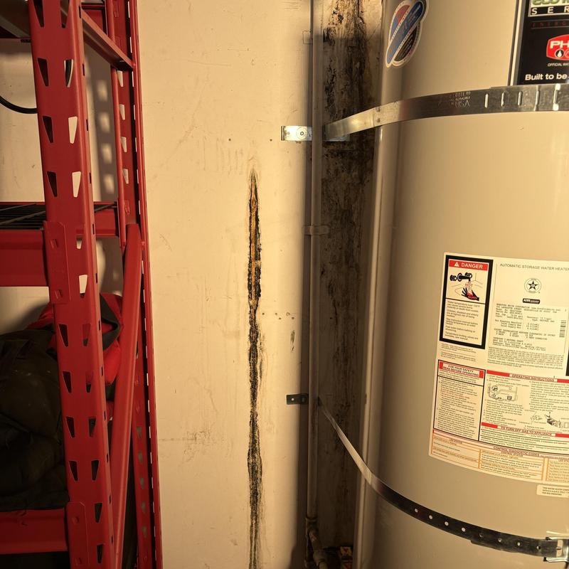 Water heater wall damage near red shelving unit