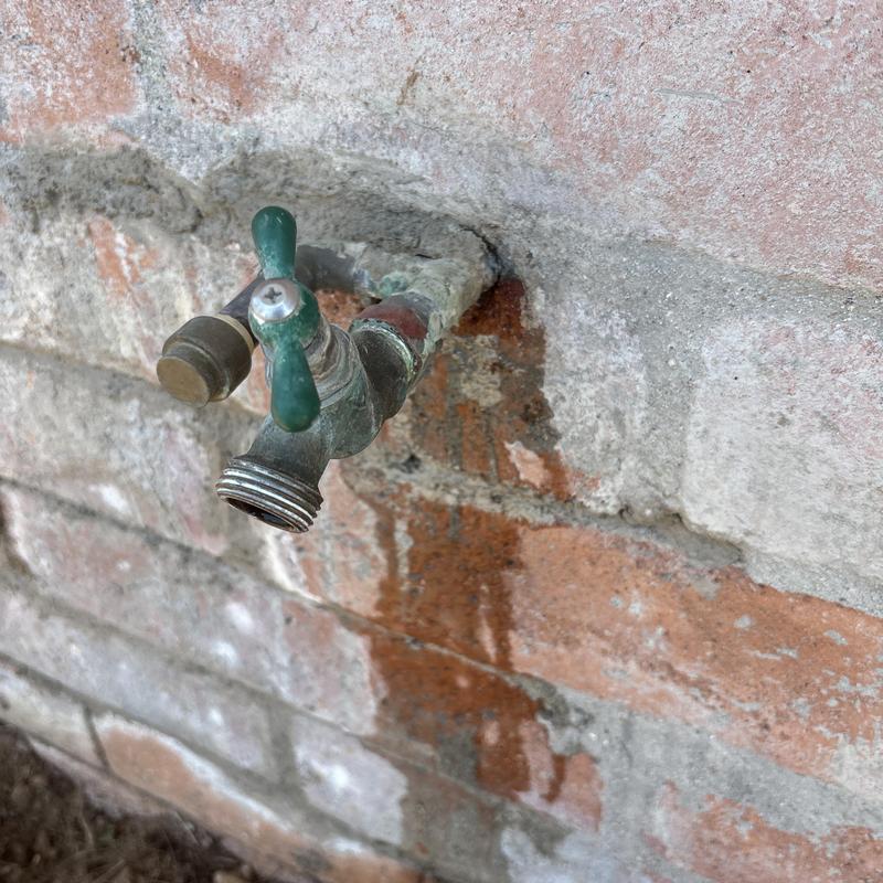 Outdoor hose bibb on brick wall with corrosion