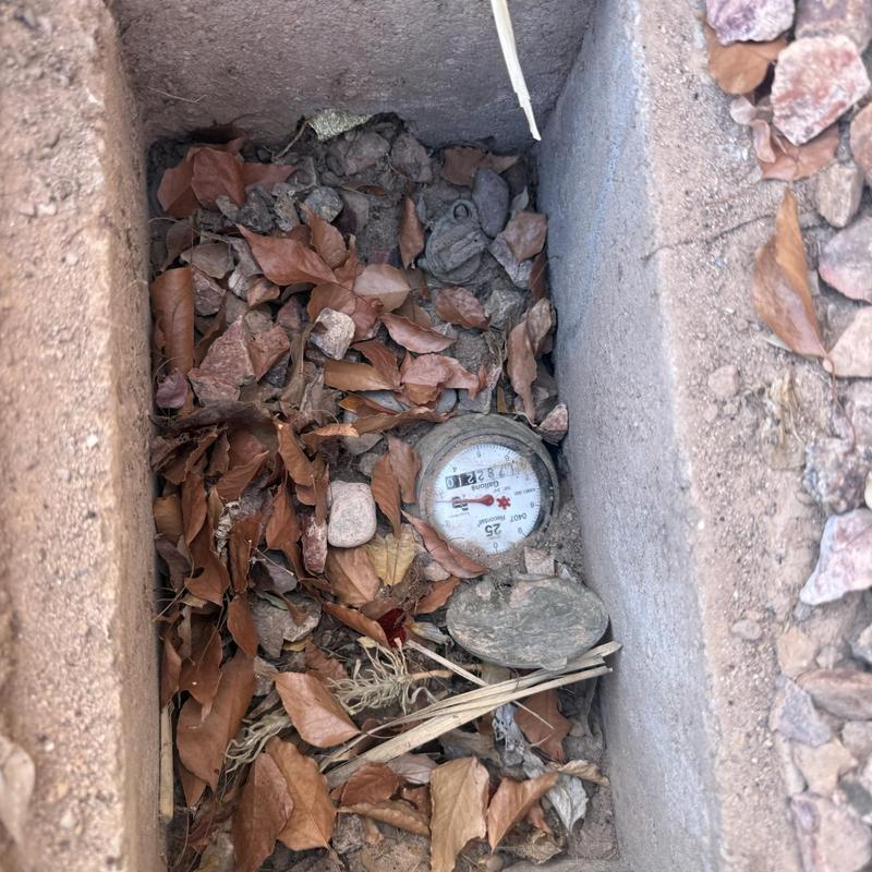 Water meter in valve box with leaves and debris