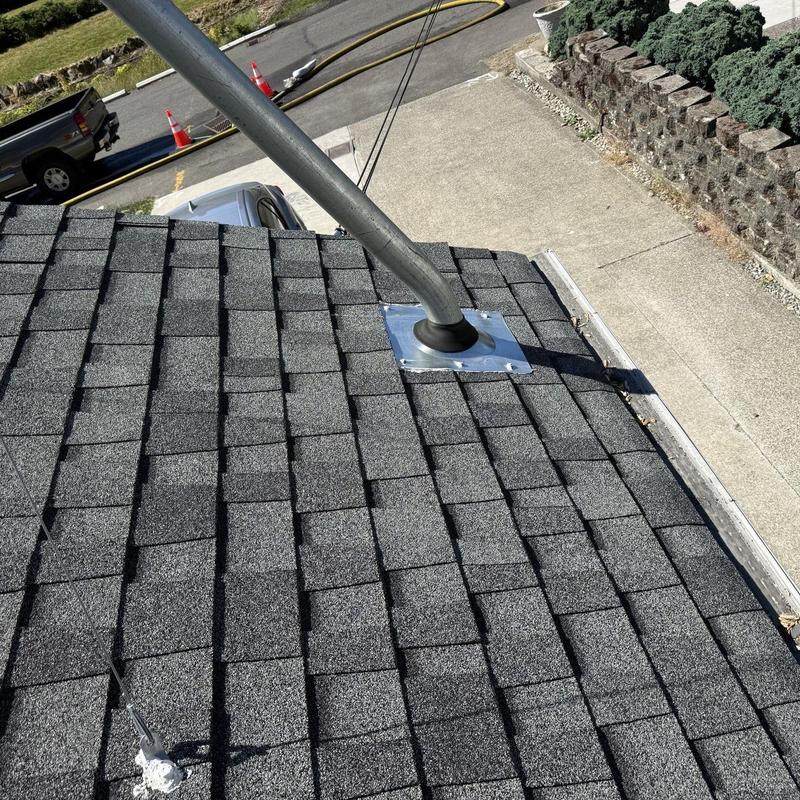 Roof pipe boot installation on gray shingle roof