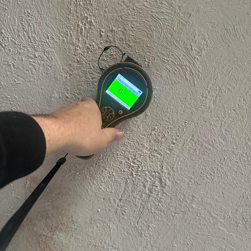 Moisture meter testing textured interior wall surface